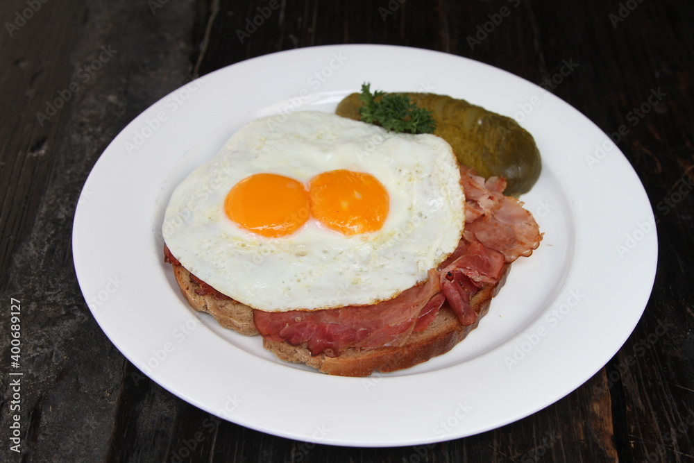 Famous German meal called Strammer Max. Fried eggs and ham on sourdough bread, served with gherkins Famous German meal called Strammer Max. Fried eggs and ham on sourdough bread, served with gherkins