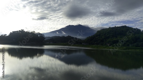 Reflection of mount Lawu and dark morning clouds in lake Buyutan in Sambirejo, Sragen, Central Java