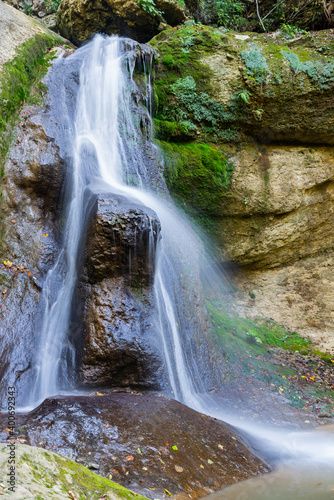 Fototapeta Naklejka Na Ścianę i Meble -  Long exposure waterfall over brown and green rocks
