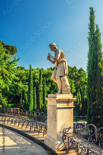 Fototapeta Naklejka Na Ścianę i Meble -  Androne monument statue and metal iron benches in Villa Bellini park in Catania historical city centre of Sicily island, clear blue sky background, southern Italy