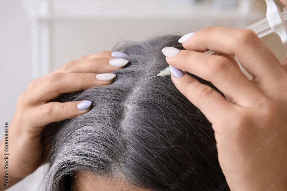 Naklejka premium Woman with graying hair using serum at home, closeup