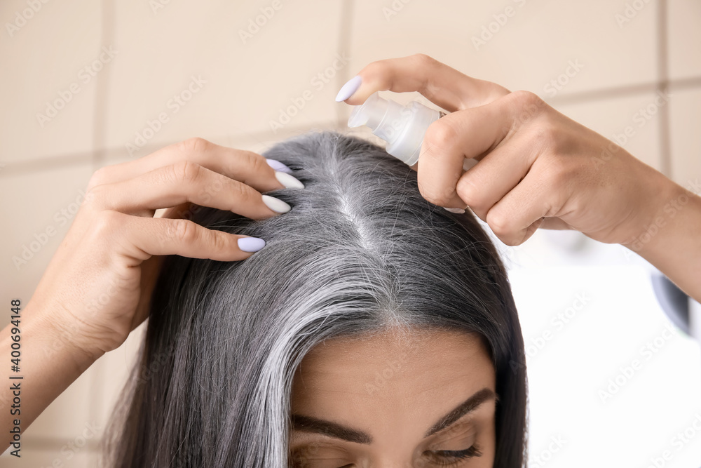 Naklejka premium Woman with graying hair using serum at home, closeup