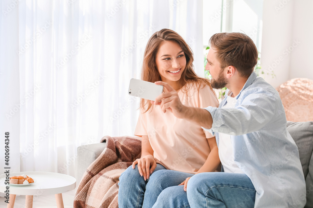 Fototapeta premium Young couple taking selfie at home