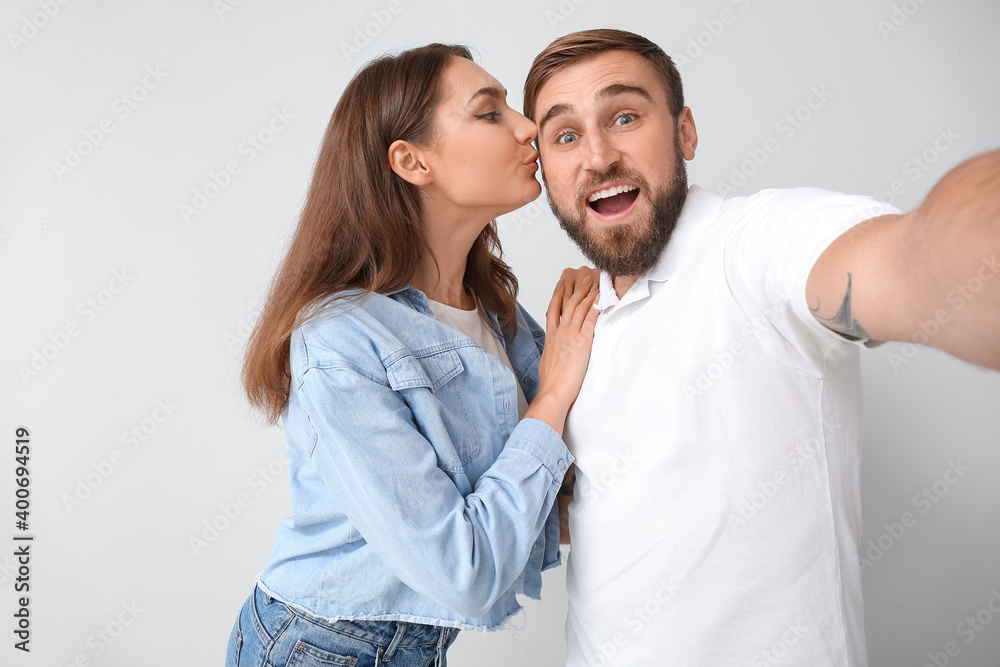 Young couple taking selfie on light background Young couple taking selfie on light background