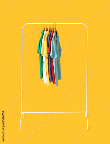 Rack with clothes on color background