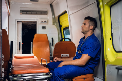 Overworked paramedic sitting inside the ambulance car.