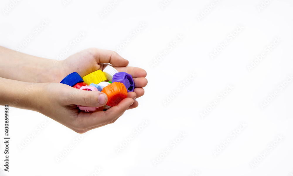 Children's hands hold plastic bottle caps on a white background. Ecology and recycling concept.