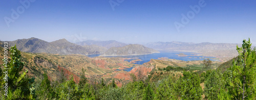 Stunning panoramic view of Nurek dam lake on the Vakhsh river, second highest in world between Dushanbe and Khatlon regions in Tajikistan with trees foreground photo