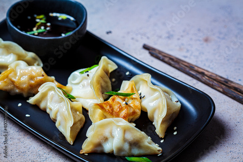 Φωτογραφία Fried gyoza dumplings with sauce and green onions on black plate, dark background