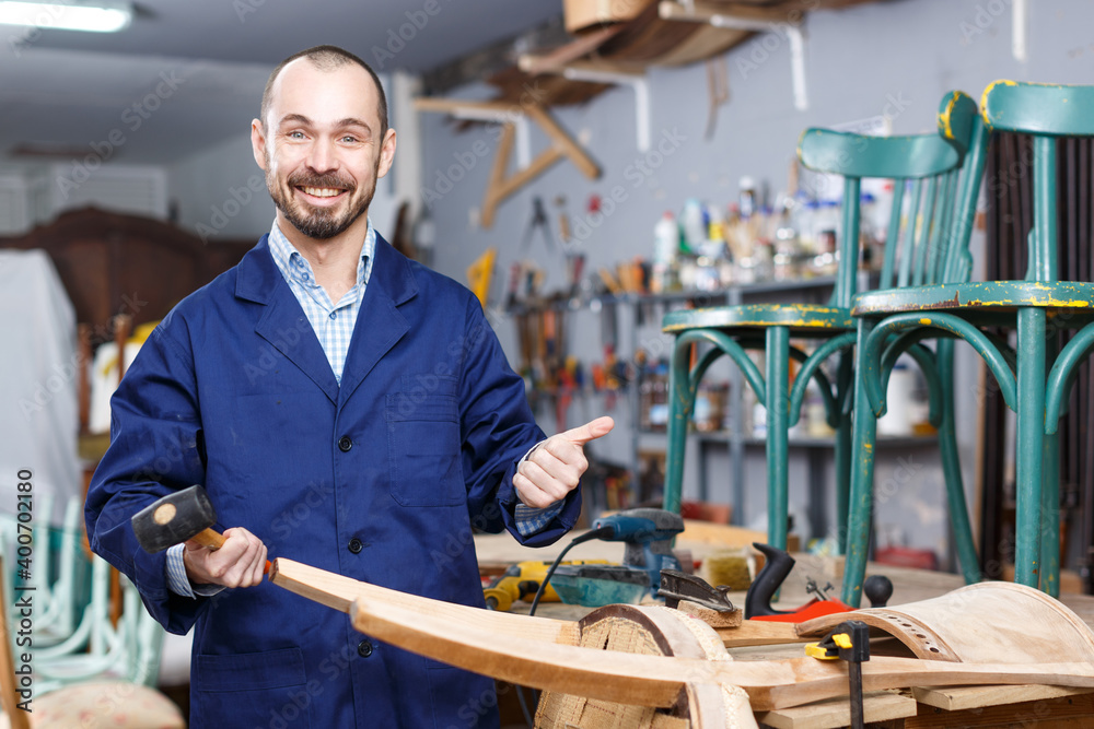 Confident workman using tools while working at repair shop, renovating vintage chair