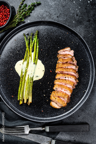 Roast duck fillet with asparagus, herbs and spices. Black background. Top view.