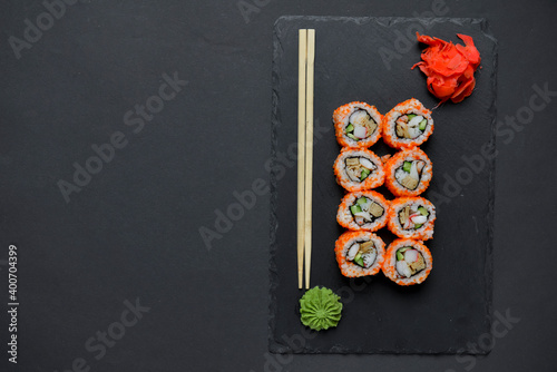Different Sushi rolls, sushi set rolled in cheese. California philadelphia sushi rools served on a black chalk board.