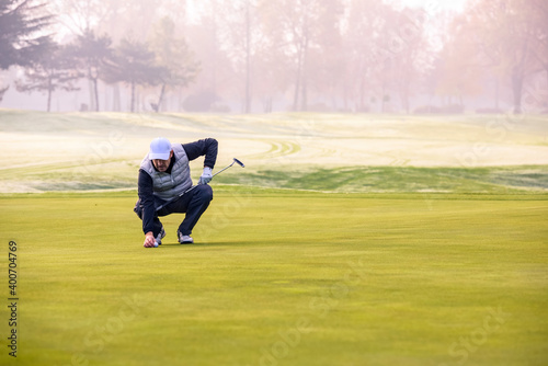Close-up of a golf player on course aiming for put shot during a tournament