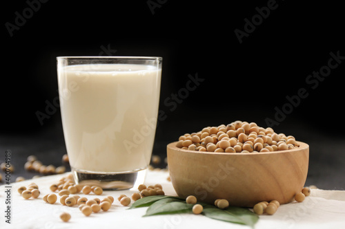 Soy milk with soybeans on dark background.