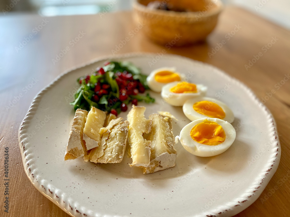 Healthy Homemade Breakfast Plate with Moldy Cheese, Boiled Eggs, Rucola Arugula or Rocket Leaves with Pomegranate Seeds on Wooden Table. Healthy Homemade Breakfast Plate with Moldy Cheese, Boiled Eggs, Rucola Arugula or Rocket Leaves with Pomegranate Seeds on Wooden Table.