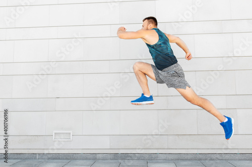 fitness, sport and healthy lifestyle concept - young man running or jumping outdoors