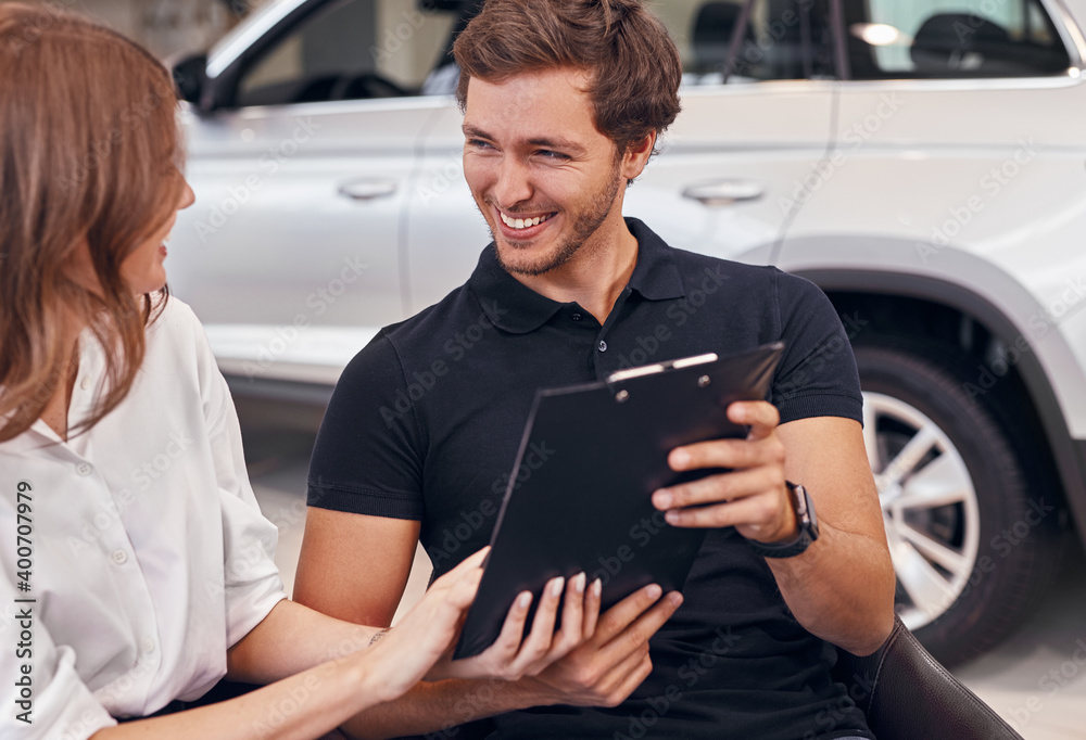 Fototapeta premium Happy couple reading contract in car dealership