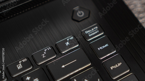 Flight mode button, F12 key, airplane button on keyboard. Laptop flat profile backlit keyboard airplane flight mode key closeup