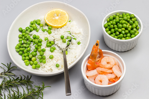 Boiled basmati rice with green peas in plate. Shrimp and green peas in bowls