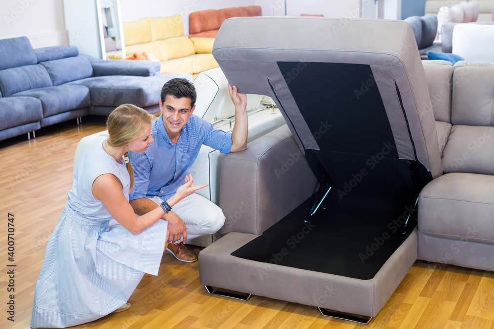Obraz premium Family couple are choosing new sofa with a rising bottom in furniture store.