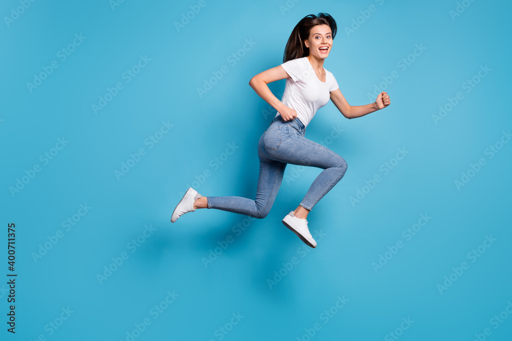 Full size profile side photo of cheerful charming lady jump up run empty space sale hurry isolated on blue color background