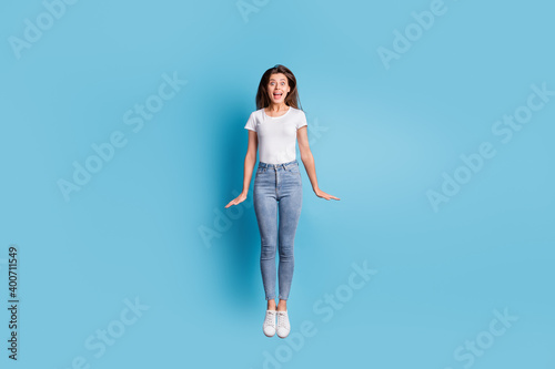 Full body photo of crazy shocked woman jump air unexpected dream travel isolated on blue color background