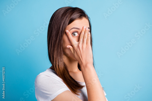 Photo of guilty scared young lady wear white clothes arm cover face watch eye isolated blue color background