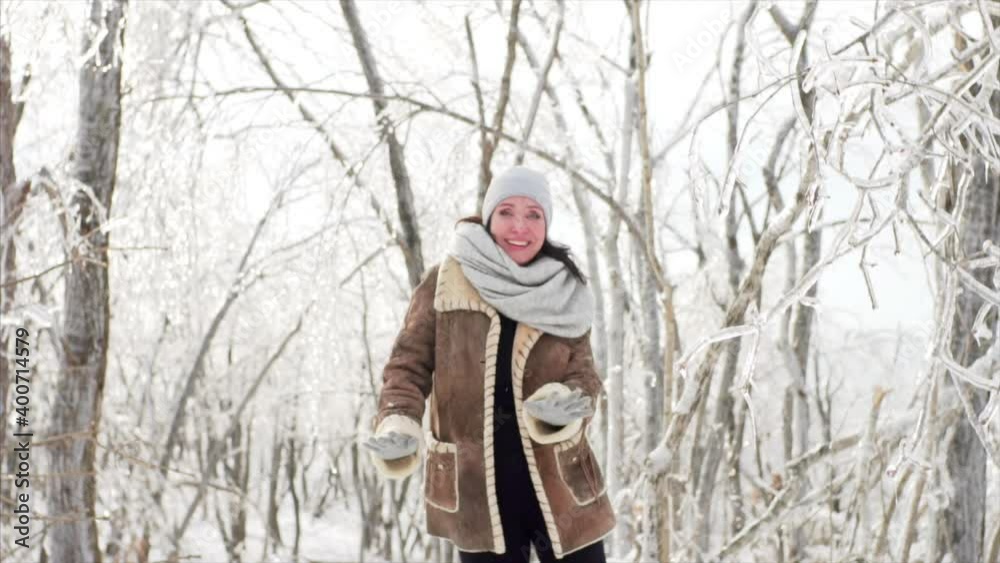 Happy middle-aged woman is dancing in the forest where branches are covered with ice after icy rain, natural disaster. Russia Happy middle-aged woman is dancing in the forest where branches are covered with ice after icy rain, natural disaster. Russia