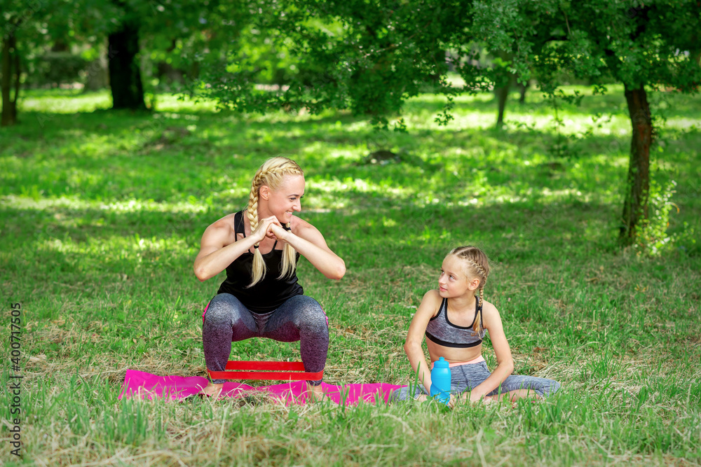Mother and daughter doing sports exercises on the mat in the park outdoor Mother and daughter doing sports exercises on the mat in the park outdoor
