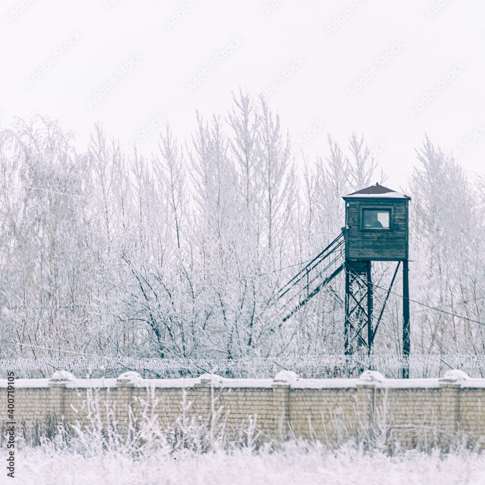 Prison tower at the fence with barbed wire. in winter in the snow Soft focus Prison tower at the fence with barbed wire. in winter in the snow Soft focus