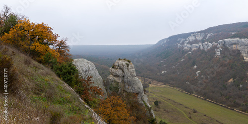 Mountains, autumn forest and fog. Beautiful morning in a mountain valley. Panoramic landscape of misty mountains with oak forest. The cave city of Eski-Kermen in the Bakhchisarai district of Crimea