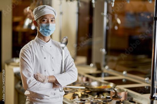 Young Asian chef posing proudly in his kitchen