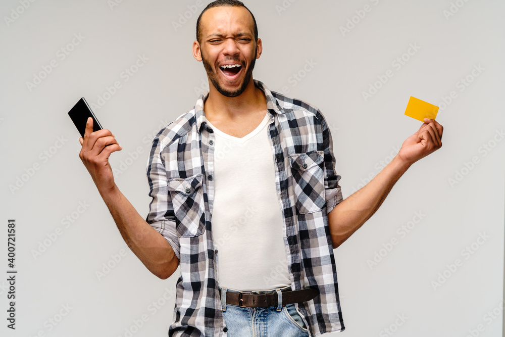 Portrait of a young african american man holding mobile cell phone and credit or discount card Portrait of a young african american man holding mobile cell phone and credit or discount card