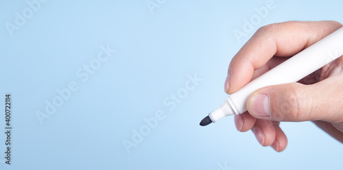 Male hand holding a marker isolated on blue background.