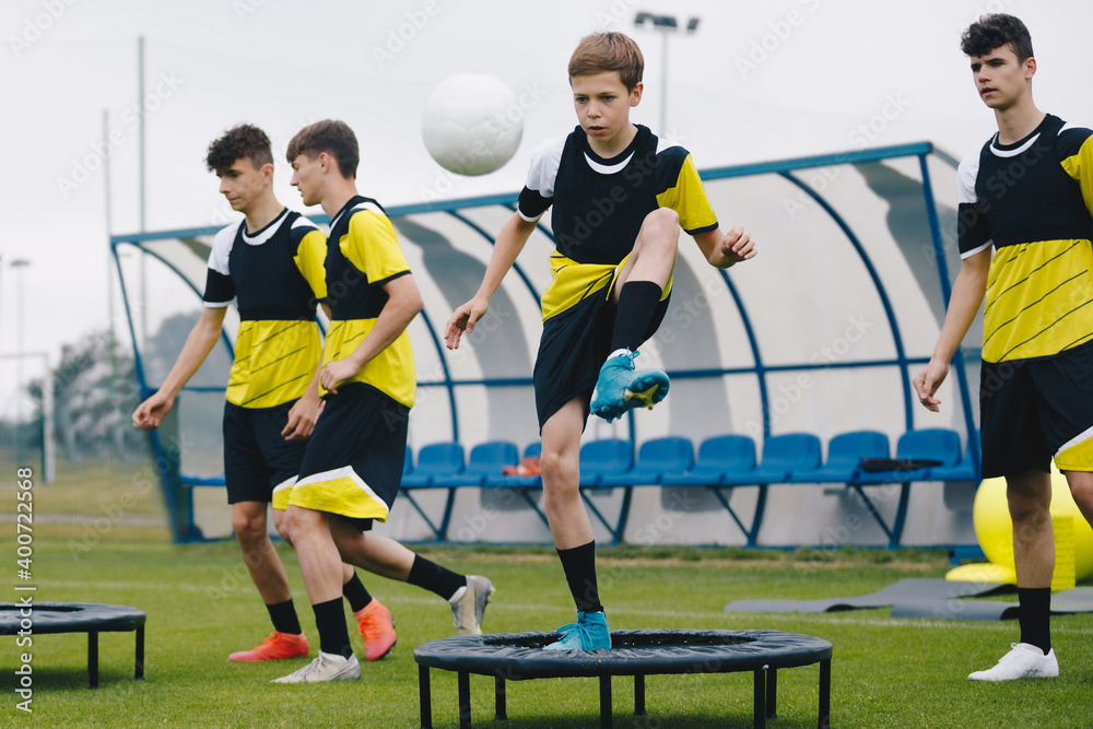 Youth on football training. Teenagers on football trampoline. Group of young boys in sports soccer club practice ball jumping on trampoline. Youth athletes improving balance skills Stock Photo
