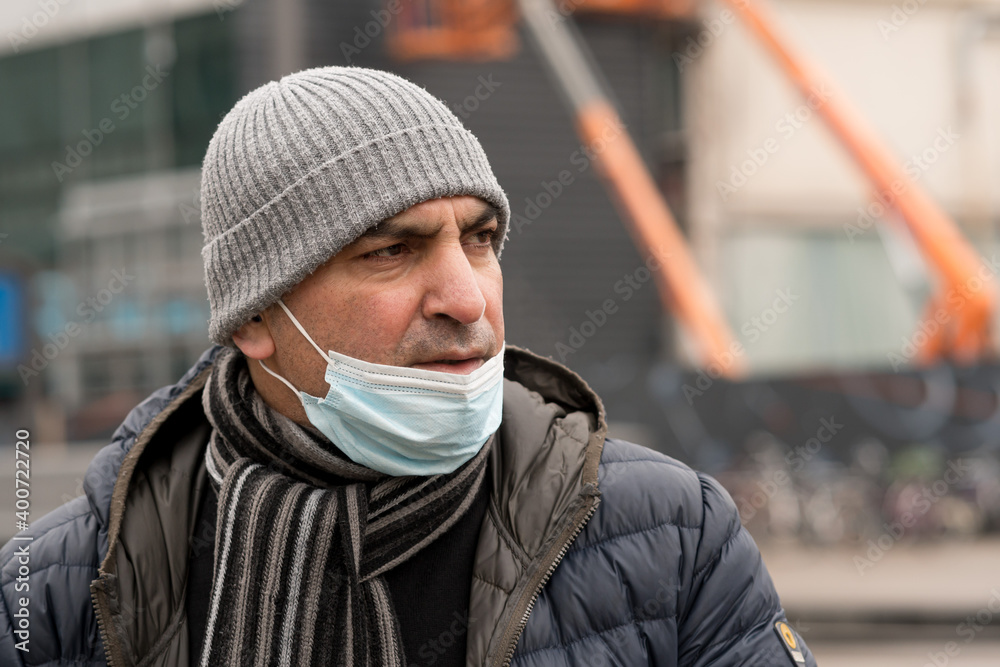 Portrait of a man with his blue protective medical face mask, lowered to the chin. Incorrect wearing of medical masks under quarantine Portrait of a man with his blue protective medical face mask, lowered to the chin. Incorrect wearing of medical masks under quarantine