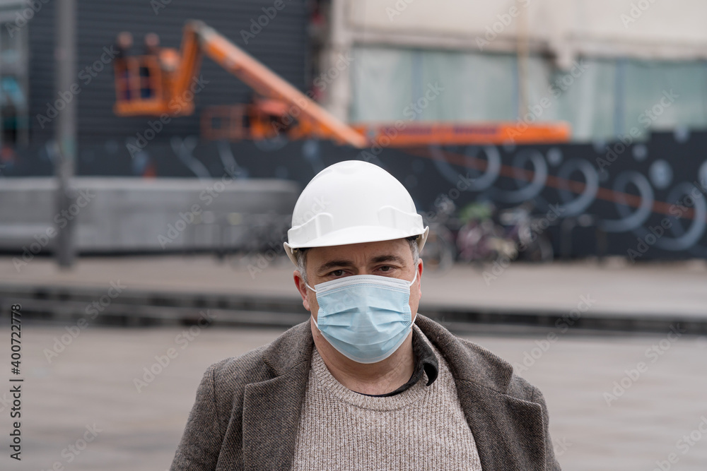 Engineering during COVID-19 (Coronavirus SARS-CoV-2) outbreak. Occupational safety and health and protection against adverse conditions at work. Construction worker wearing hardhat and medical mask Engineering during COVID-19 (Coronavirus SARS-CoV-2) outbreak. Occupational safety and health and protection against adverse conditions at work. Construction worker wearing hardhat and medical mask