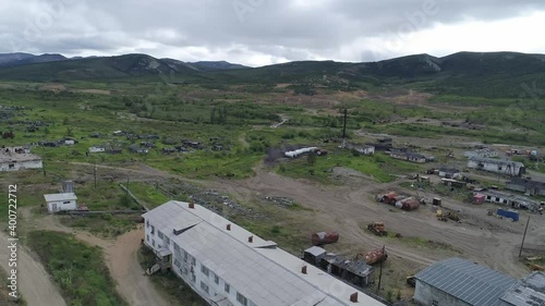 Aerial view of the abandoned village located between the hills. There are two-storey houses and one-storey wooden houses in the village. Many houses have been destroyed. There is a lot of metal debris photo