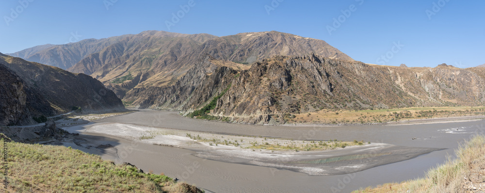 Epic panoramic landscape view of the Panj river valley in Darvaz district, Gorno-Badakshan, the Pamir mountain region of Tajikistan with sandbank