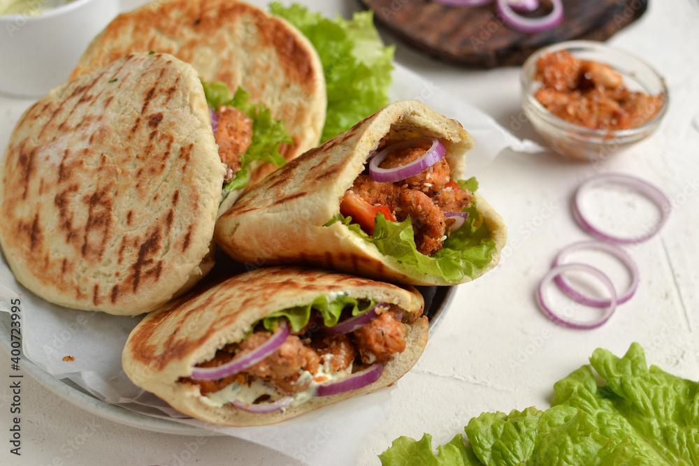 Lavash salad with fried chicken and vegetables. Pita with chicken nuggets, tomatoes, red onions and lettuce and sauce. Healthy fast food. Light background. Lavash salad with fried chicken and vegetables. Pita with chicken nuggets, tomatoes, red onions and lettuce and sauce. Healthy fast food. Light background.