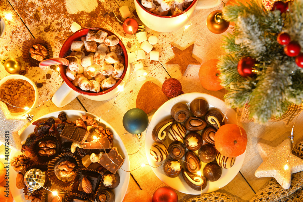 sweet food top view background for merry christmas or new year holiday decoration with night illumination - chocolate candies, tangerines, cookies, marshmallow and cocoa latte on white wood sweet food top view background for merry christmas or new year holiday decoration with night illumination - chocolate candies, tangerines, cookies, marshmallow and cocoa latte on white wood