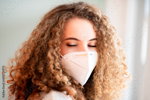 young curly hair woman wearing a medical face mask and closing eyes, close-up portrait of a face isolated on a white background