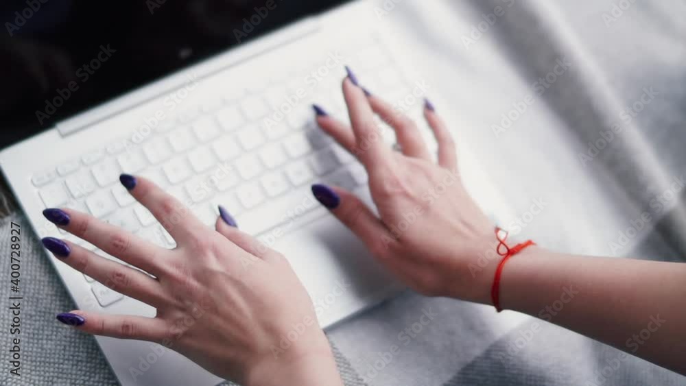 Young woman is typing something on the laptop keyboard.