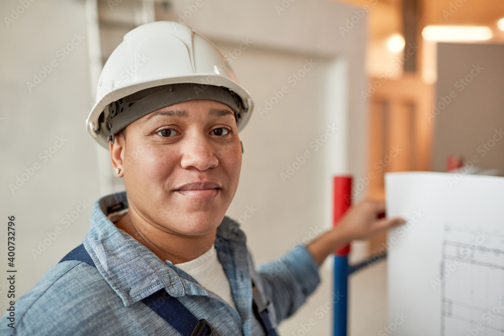 Close up portrait of mixed-race female worker looking at camera while wearing hardhat on construction site, copy space Close up portrait of mixed-race female worker looking at camera while wearing hardhat on construction site, copy space