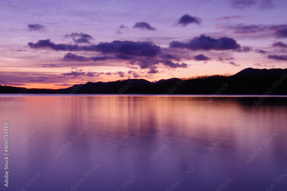 鮮やかなグラデーションの空に浮かぶ雲。湖面に映る黄昏の空が美しい明媚な風景。