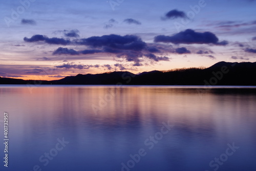 鮮やかなグラデーションの空に浮かぶ雲。湖面に映る黄昏の空が美しい明媚な風景。 © Masa Tsuchiya