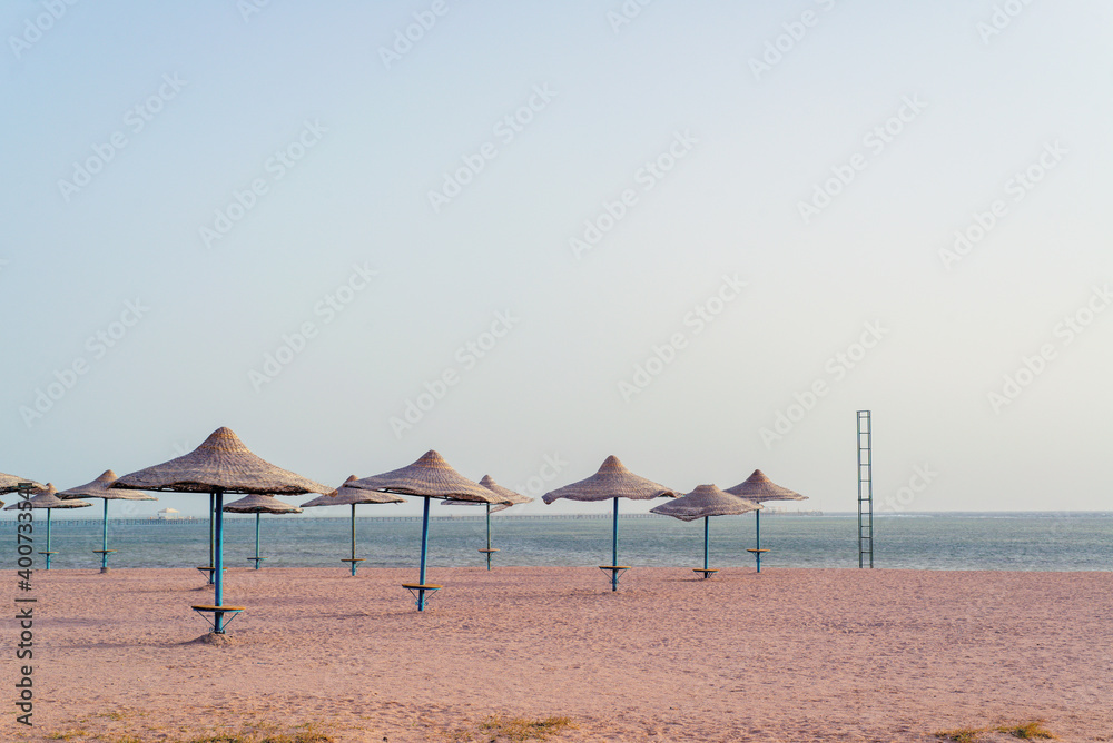 Bamboo, reed, straw umbrella on tropical island beach. Holiday relaxation with turquoise sea and blue sky landscape. Summer vacation travel concept Bamboo, reed, straw umbrella on tropical island beach. Holiday relaxation with turquoise sea and blue sky landscape. Summer vacation travel concept