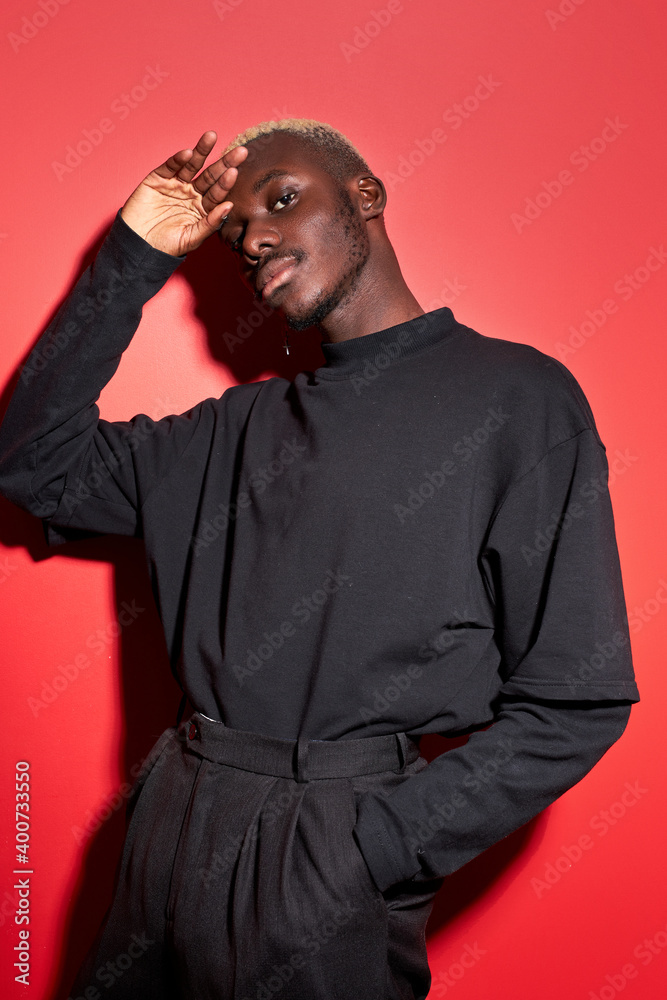 unusual portrait of afro american male model in studio with red background, fashionable stylish guy posing , wearing black fancy casual wear, in jacket and trousers unusual portrait of afro american male model in studio with red background, fashionable stylish guy posing , wearing black fancy casual wear, in jacket and trousers