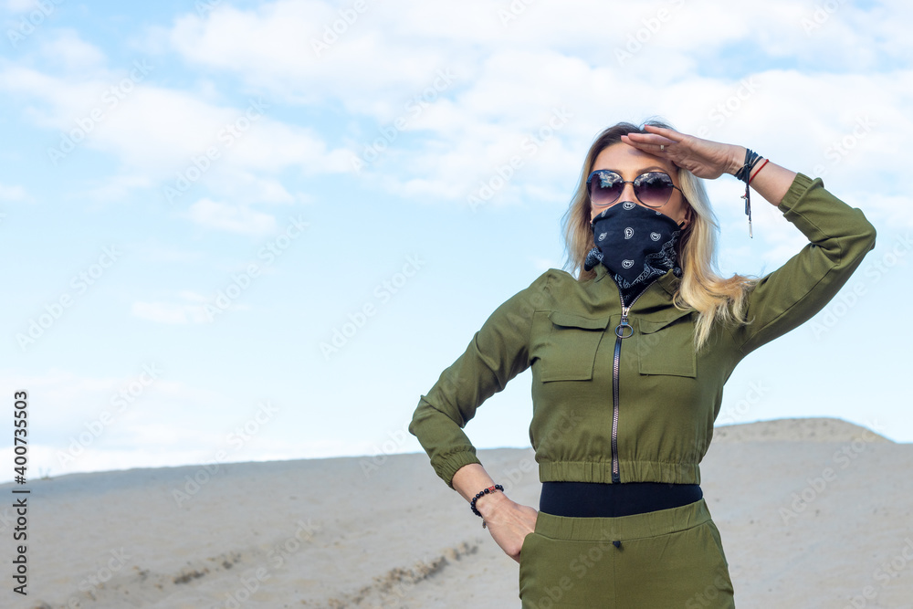 Woman with a closed face mask in protective clothing for travel to the desert, looks into the distance. Woman with a closed face mask in protective clothing for travel to the desert, looks into the distance.
