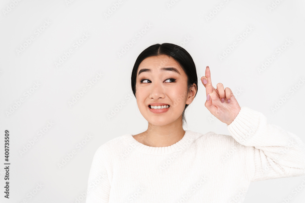 Asian confused nice girl holding fingers crossed for good luck